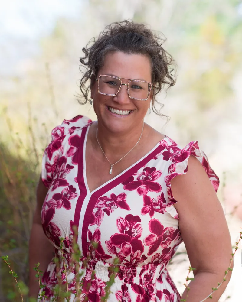 Dr. Kim Bland smiling outdoors in a floral dress